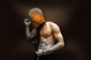 ein halbnackter Mann, dessen Kopf symbolisch durch eine leuchtende Glühbirne ersetzt wurde. Den Stecker hält er, warum auch immer, in der Hand.